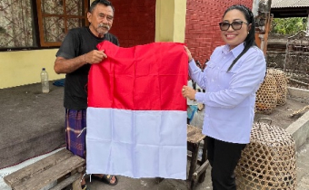 Diana Devi memberikan bendera kepada Masyarakat sekitar kantor Bawaslu Karangasem 